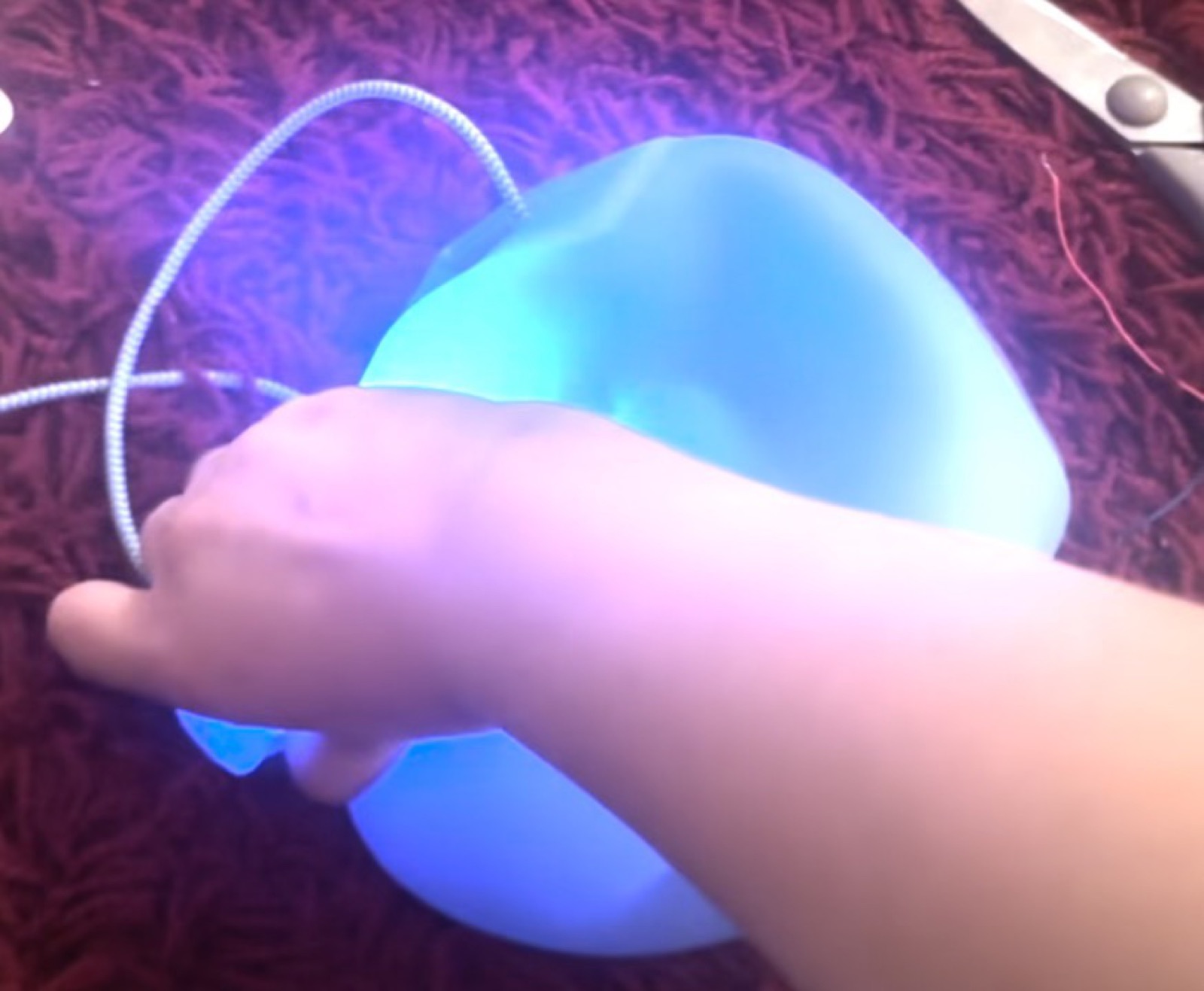 A hand squeezing the SquishyMusic orb as it glows blue and violet